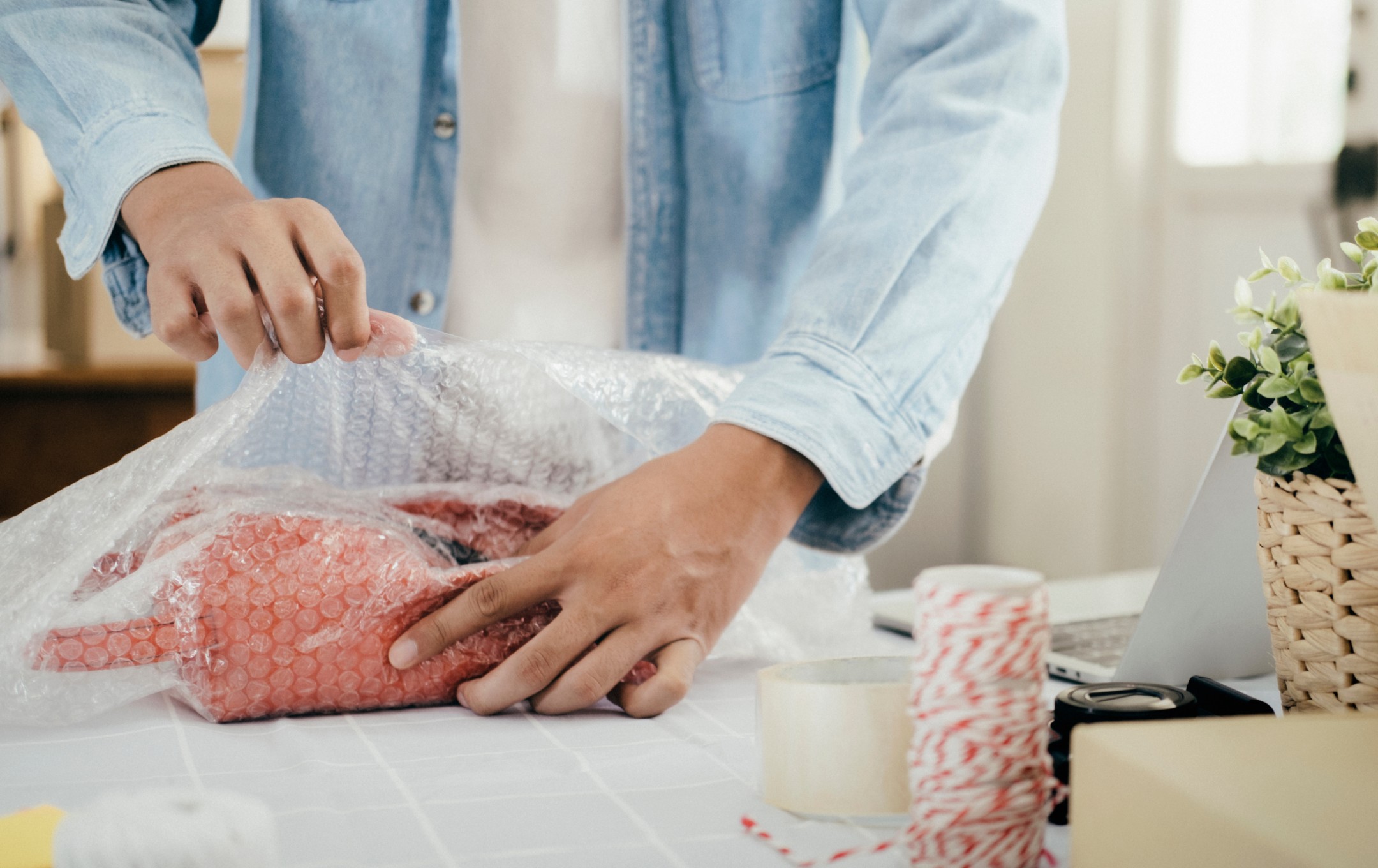 En kvinna packar in keramikkanna i bubbelplast.